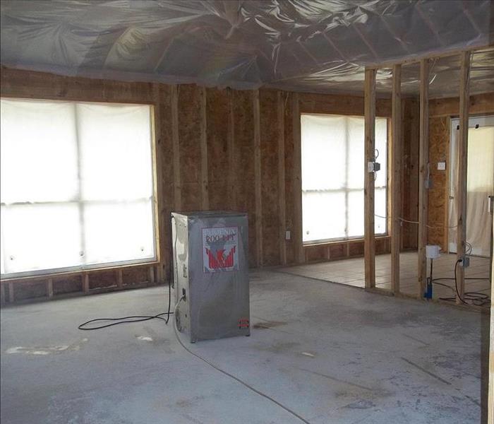 empty room with concrete floors and studs exposed, with dehumidifier 