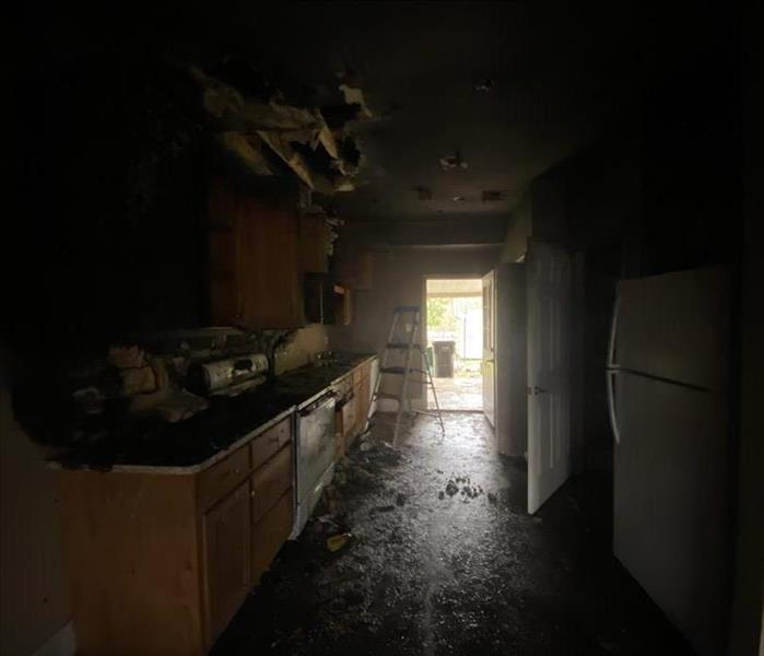 small kitchen badly damaged by fire with all cabinets black from fire and soot 