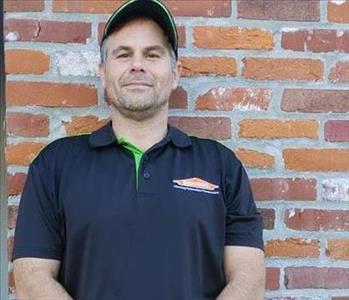man in black poo shirt with SERVPRO logo standing in front of brick wall