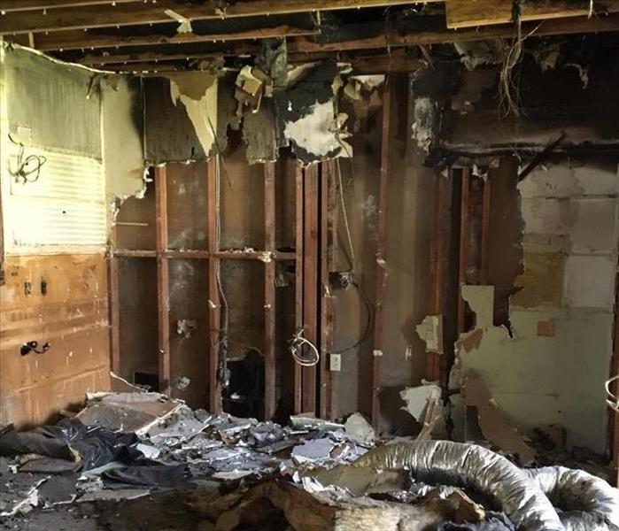 fire damaged room with exposed studs on walls and ceiling with hanging drywall
