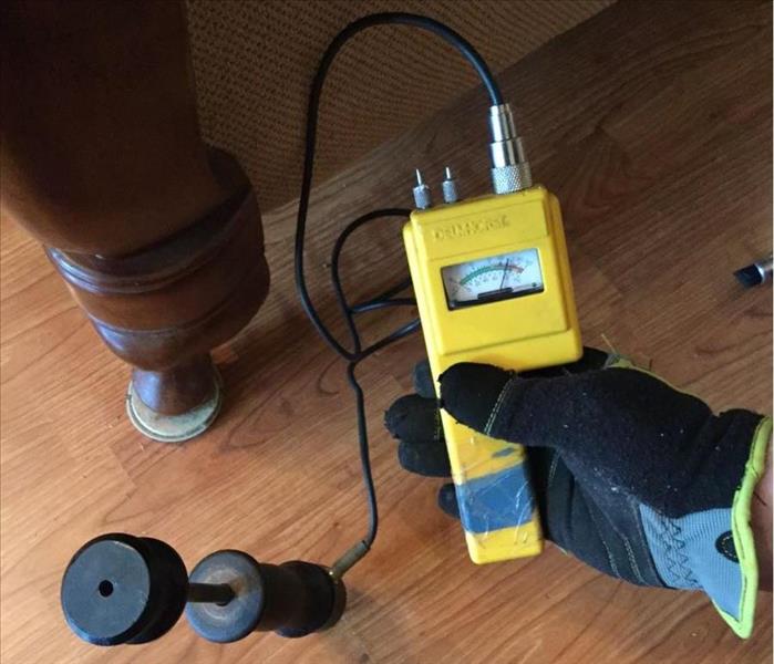 hand wearing glove using moisture probe to check moisture level of wood flooring