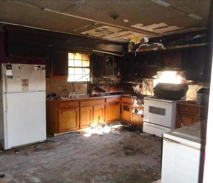 kitchen with white appliances and wooden cabinets black because of fire damage