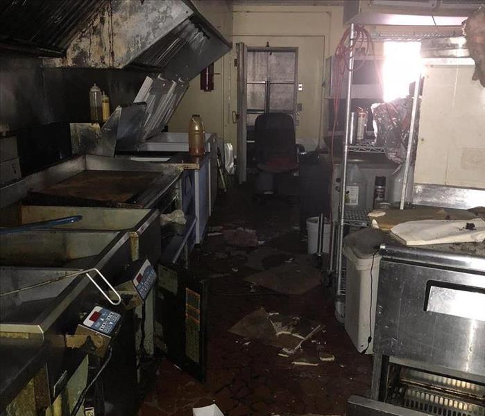 grease covered commercial kitchen with stainless steel equipment cluttered with trash 