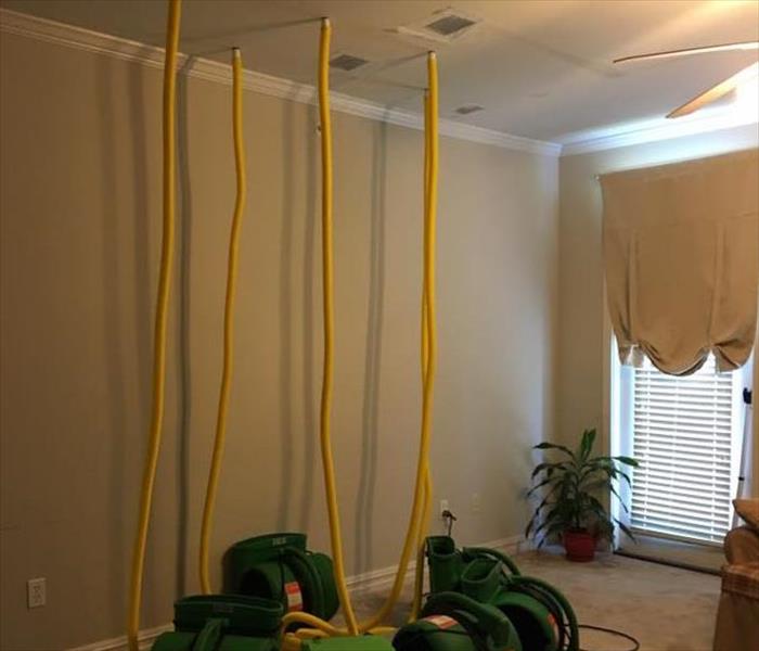 drying fan with yellow hoses stretching to ceiling in white apartment 